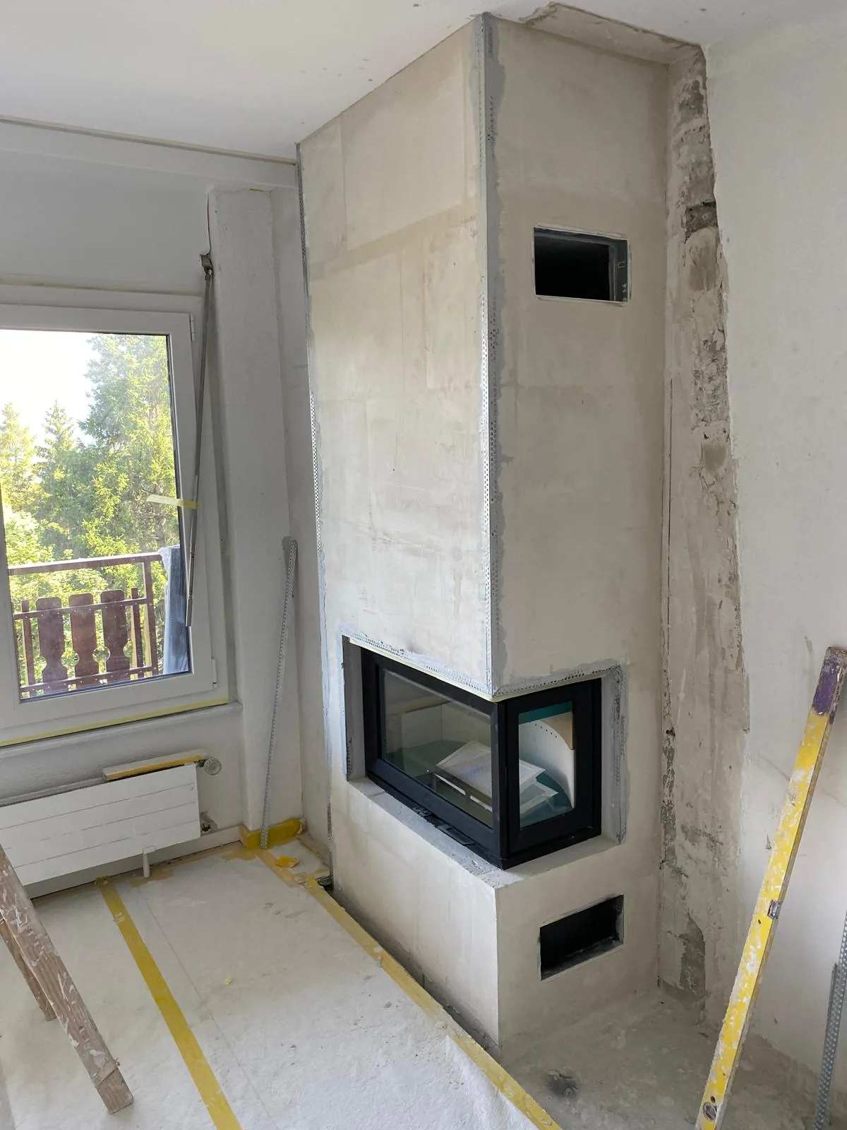 Habillage cheminée en cours d'enduit avec vitre panoramique